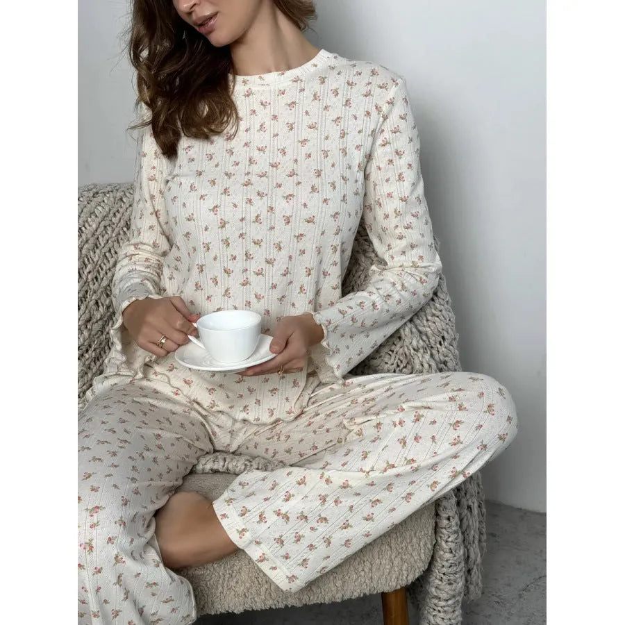 White women's floral print two-piece suit with bell sleeve top and wide-leg trousers on a hanger.
