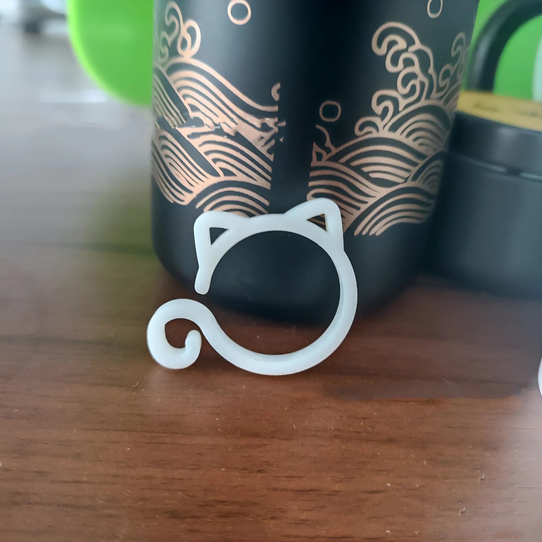 Small red cat-shaped plastic clip for plant support on a green leaf.