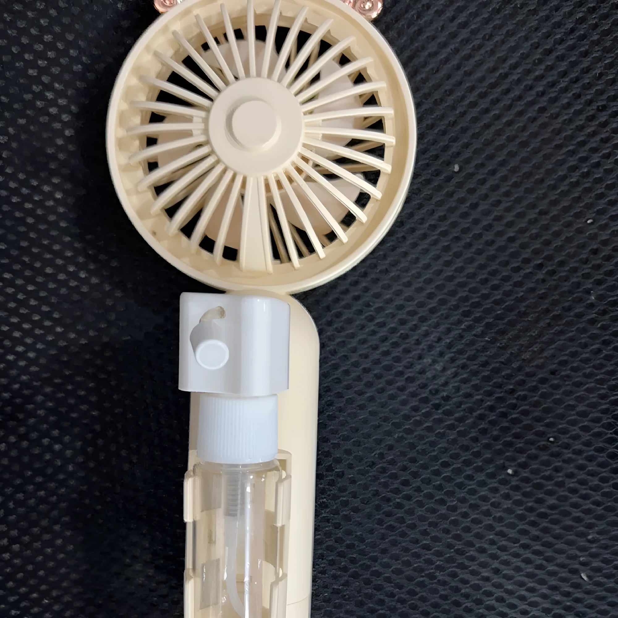 Plastic USB desk fan with a flexible nozzle in apricot colour on a wooden desk.