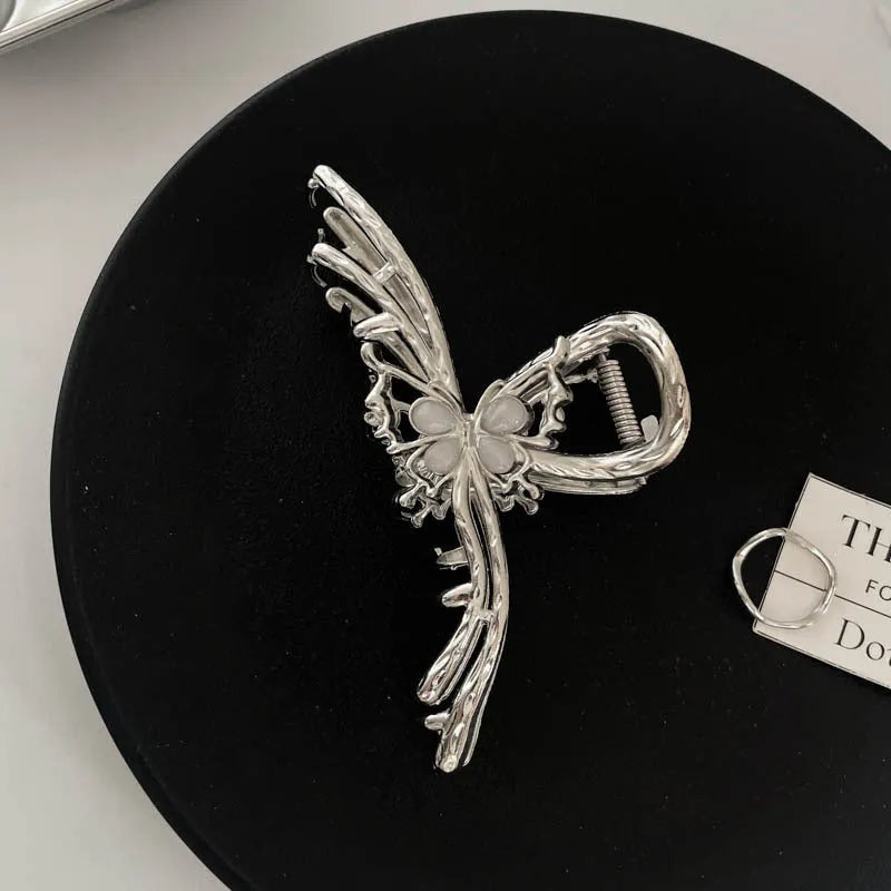 Silver metal hair claw clip assortment showing bows, waves, pearl designs, and geometric shapes from 4cm to 13.5cm