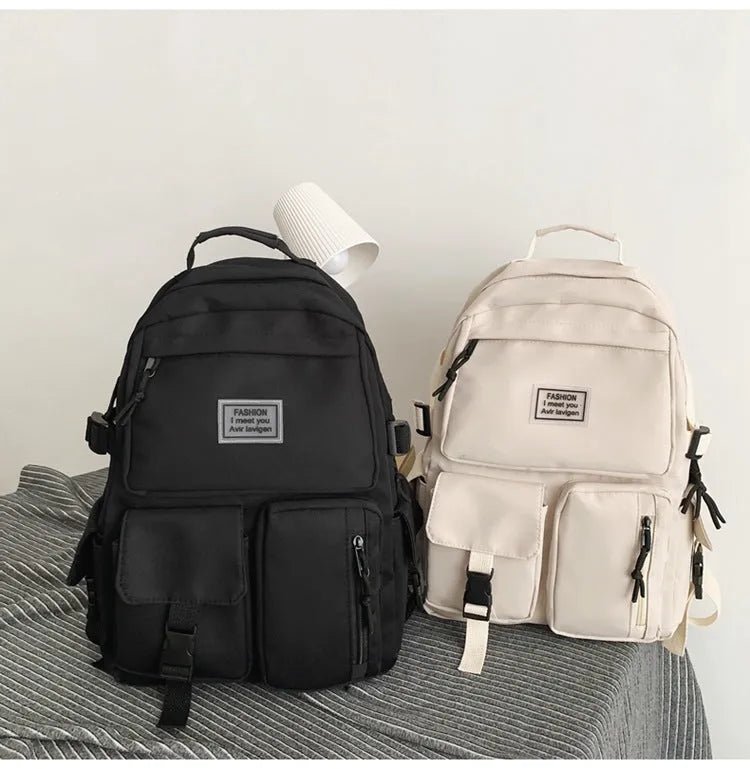 Black and white nylon student backpack with front 3D pockets, shown with laptop in compartment.