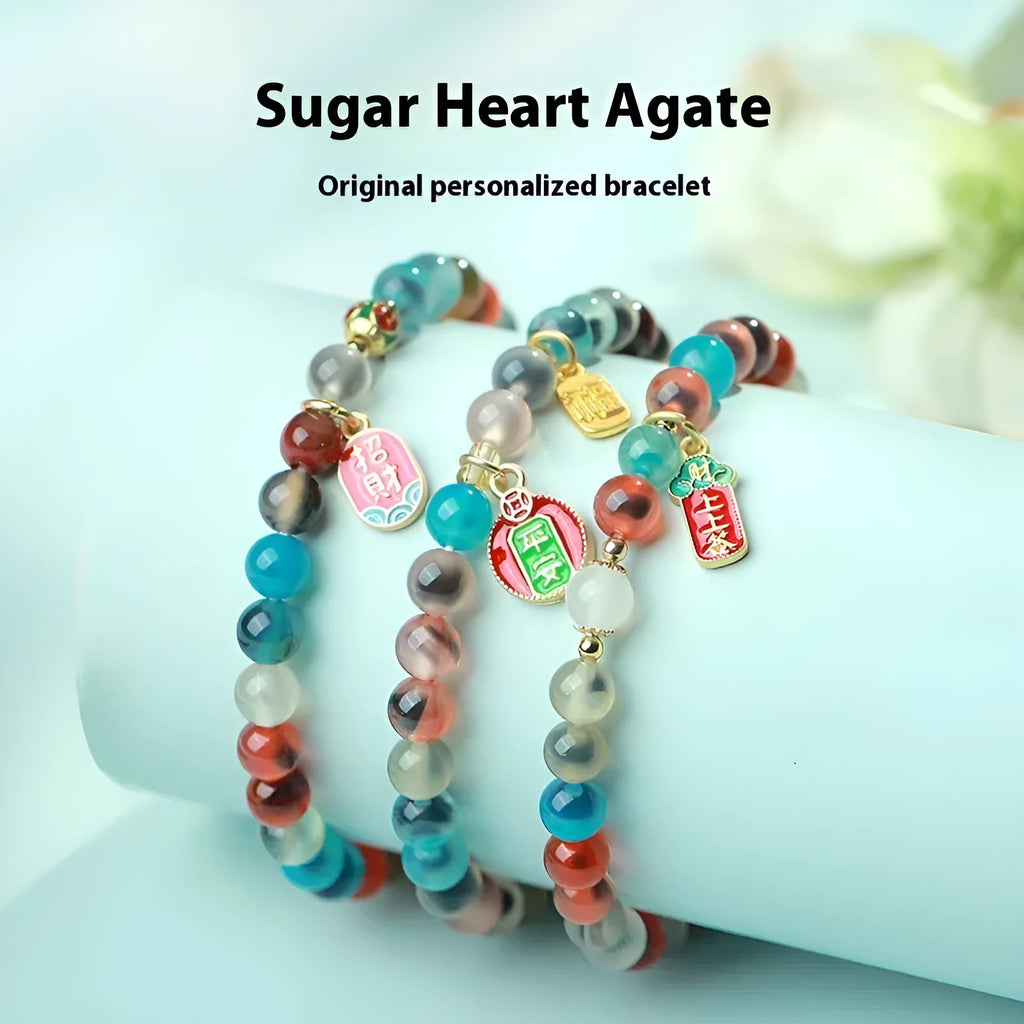Close-up of a women's snake chain bracelet with colourful agate hearts and detailed copper coins.