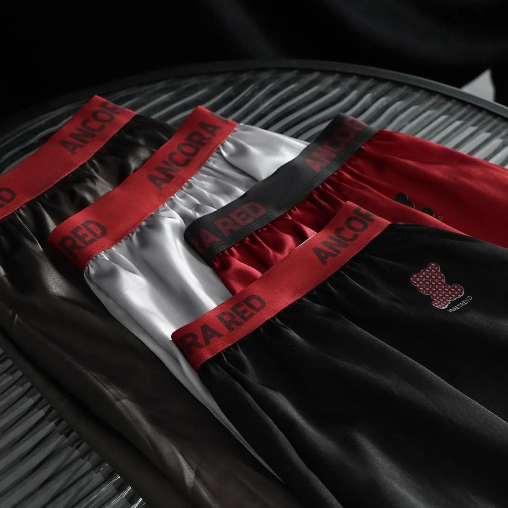 Men's solid colour knitted polyester boxer briefs on a mid-waist model, showing colour options black, blue, red, silver, purple, and brown.