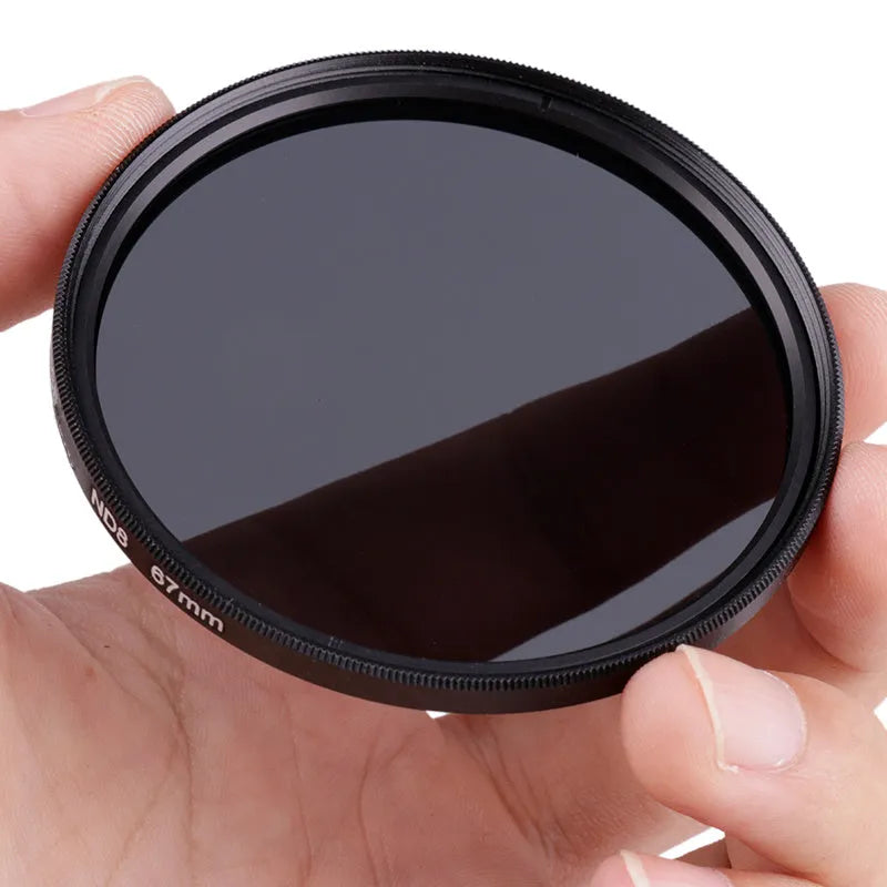 ND8 neutral density camera filter reducer with aviation aluminium frame shown next to lens.