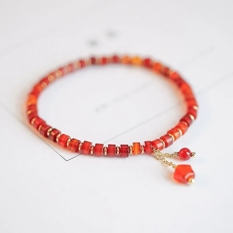 Hand-woven red agate bead bracelet with ethnic design on a wrist.