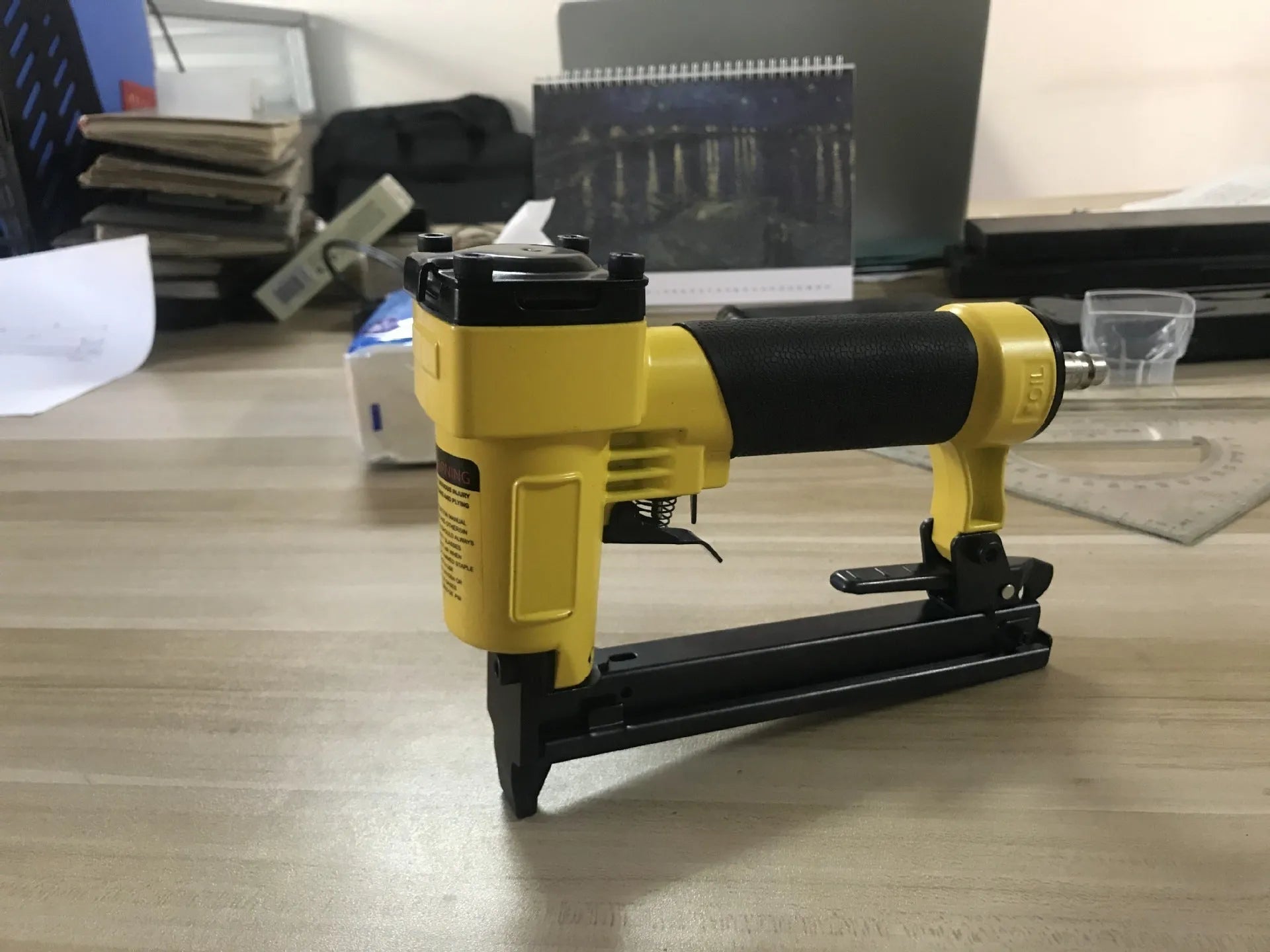Blue and yellow U-type pneumatic strip nail gun for decoration and upholstery work.
