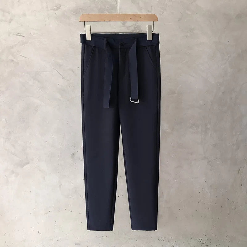 Boy wearing slim straight wool trousers in a neutral colour, showcasing the tapered fit and straight leg opening.