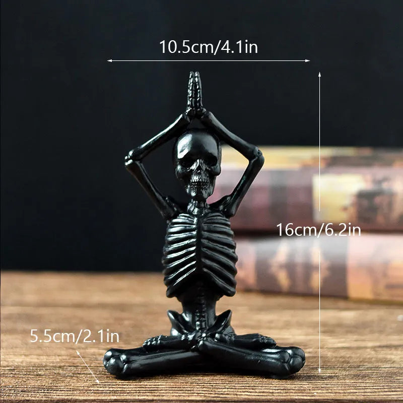 Detailed resin ornament of a yoga pose skeleton skull on a desktop, shown in black and white colour options.