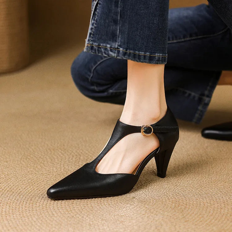 Women's brown retro T-strap closed toe sandals with a stout heel on a wooden surface