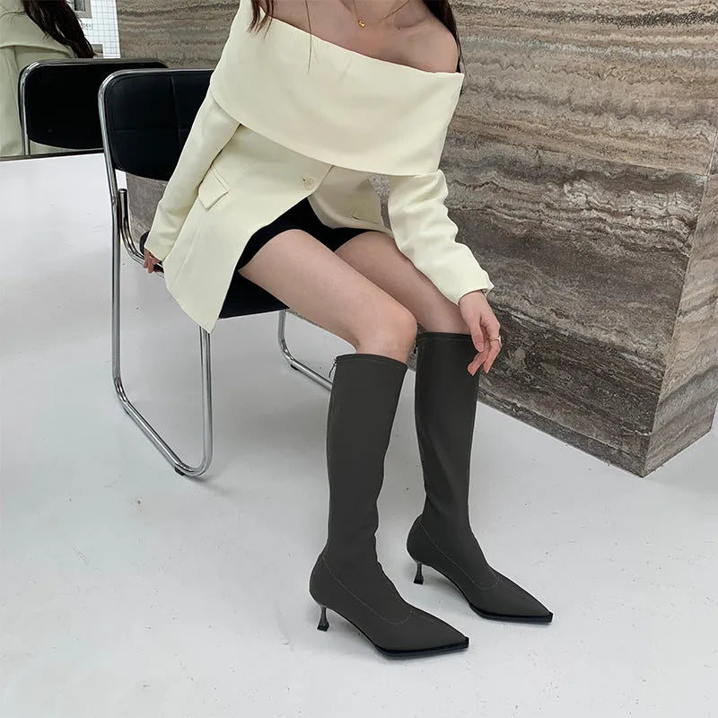 Women's black pointed toe stiletto heel boots with a back zip, shown from the side.