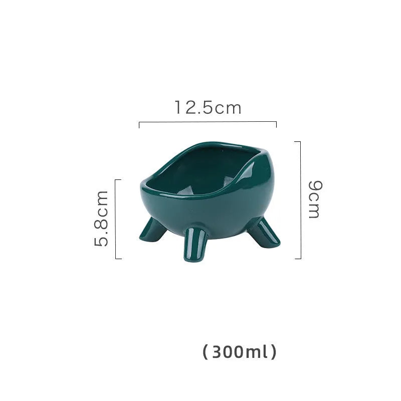 Green ceramic cat food bowl with four legs and rounded arc design on wooden floor