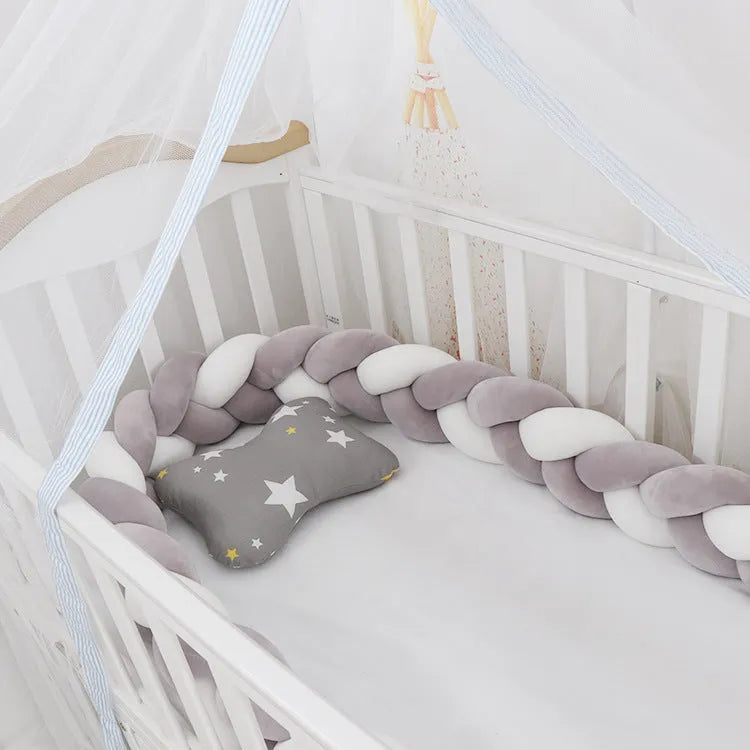Bendable braid-knot baby crib bumper in spandex velvet, shown in a light grey colour wrapped around a cot.