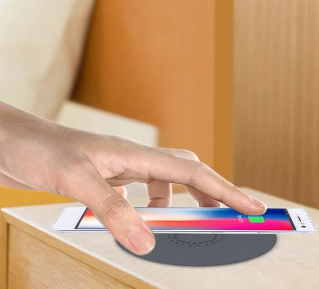 Round hidden wireless charger for embedding in desks, compatible with iPhone and Samsung phones.