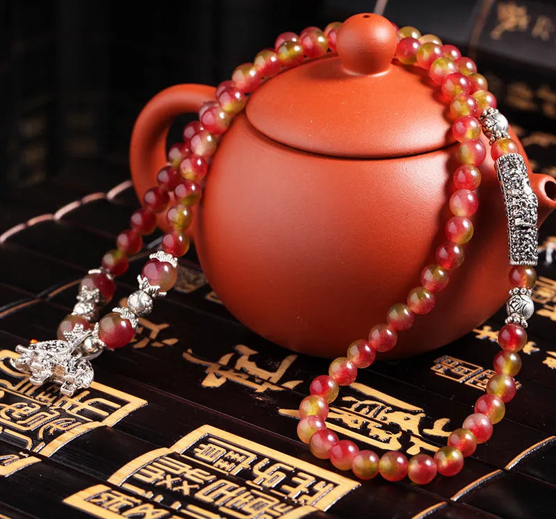 Natural watermelon crystal bracelet with a handmade Chinese knot closure, showing geometric beads.