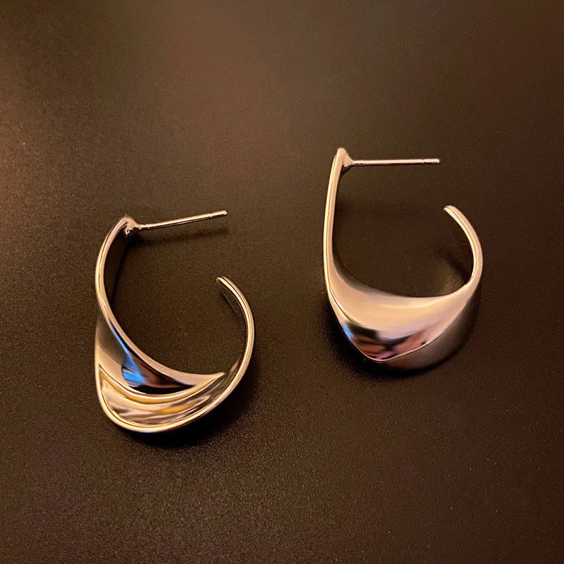 Gold and silver twisted geometric metal earrings with round shape and electroplated finish