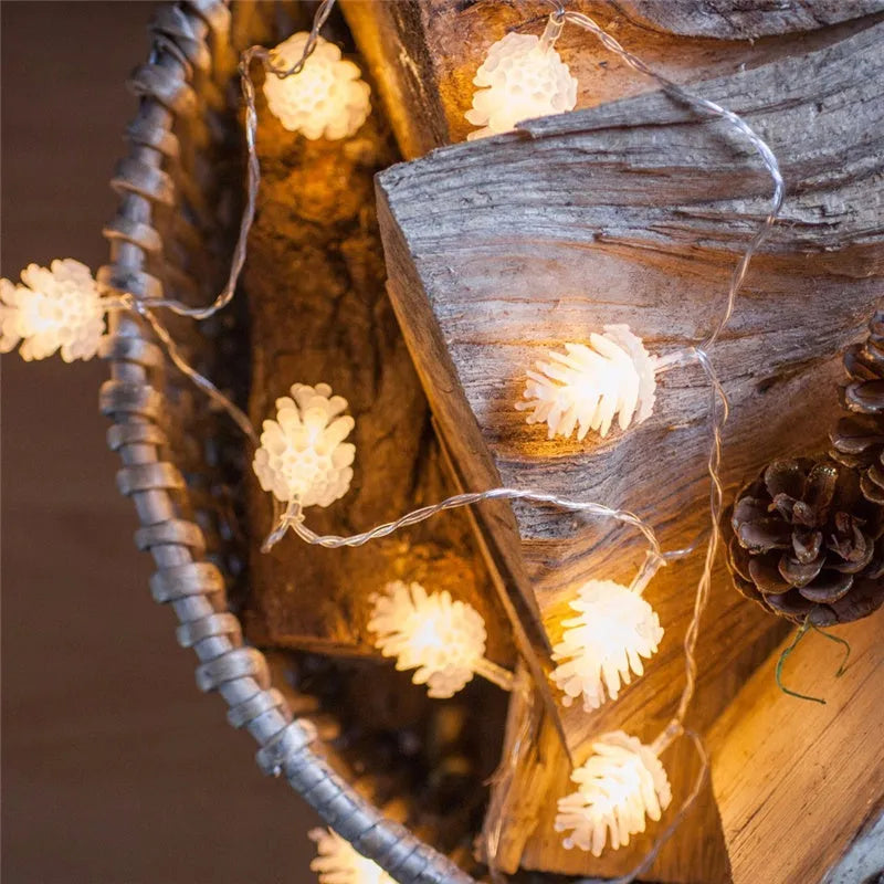 Warm white LED pine cone light string with plastic shells, powered by two AA batteries.
