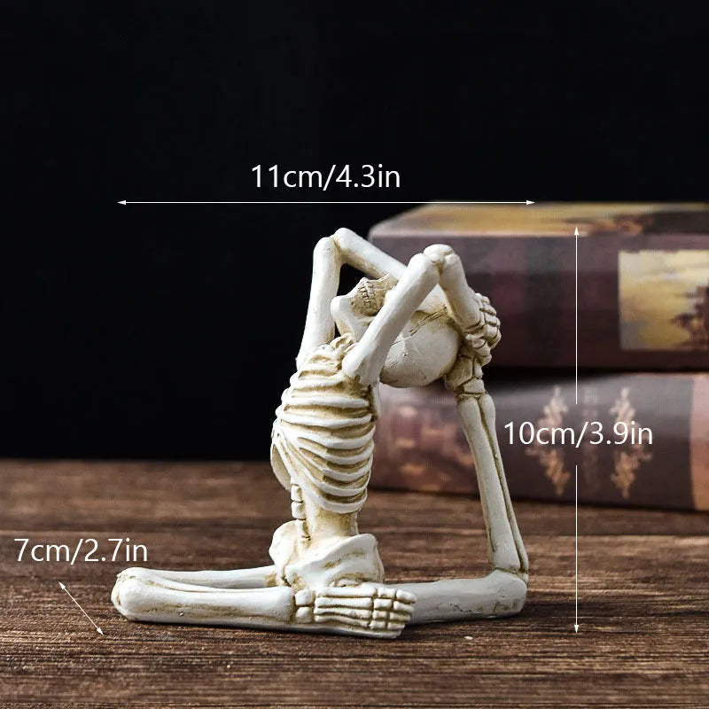 Detailed resin ornament of a yoga pose skeleton skull on a desktop, shown in black and white colour options.