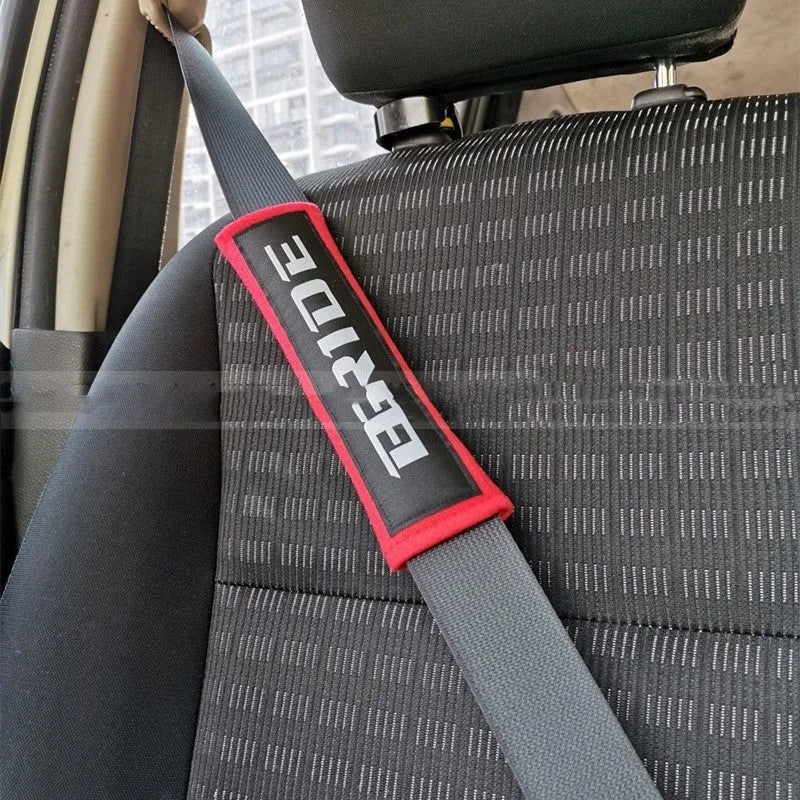 Pair of black car seatbelt shoulder pads with embroidered texture, showing dimensions.