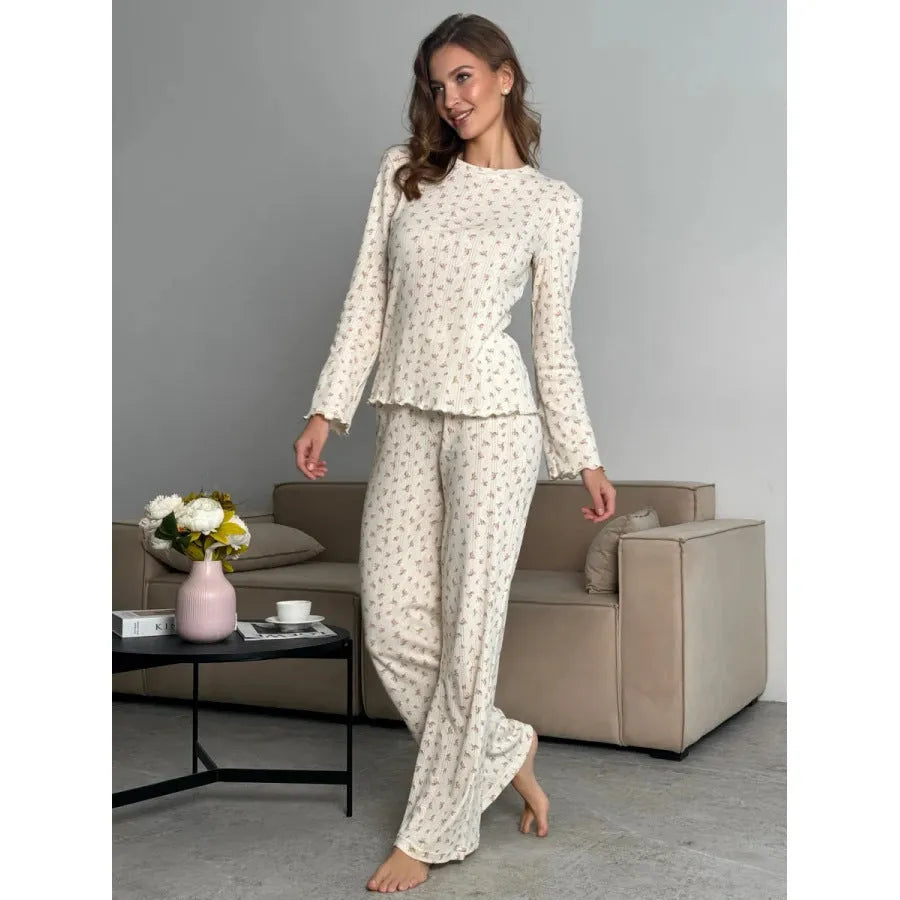 White women's floral print two-piece suit with bell sleeve top and wide-leg trousers on a hanger.