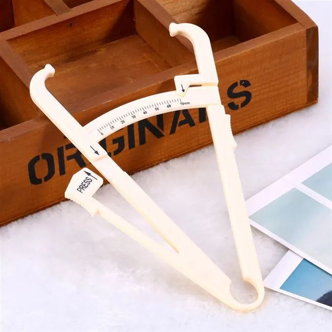 Clear acrylic body fat caliper showing measurement scales for skin fold thickness assessment