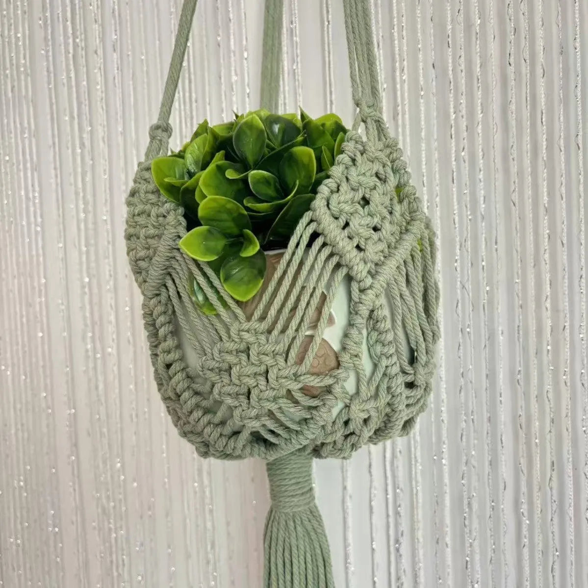 Hand-woven polyester cotton flower pot net pocket in brown, hanging with a green plant.