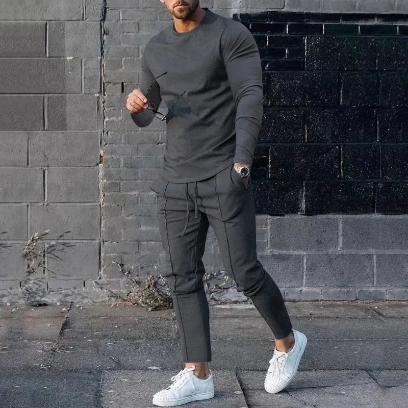 Men's light grey polyester two-piece suit with long sleeve round neck T-shirt and matching trousers laid flat.