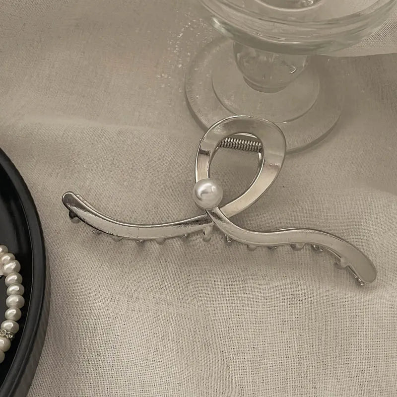 Silver metal hair claw clip assortment showing bows, waves, pearl designs, and geometric shapes from 4cm to 13.5cm