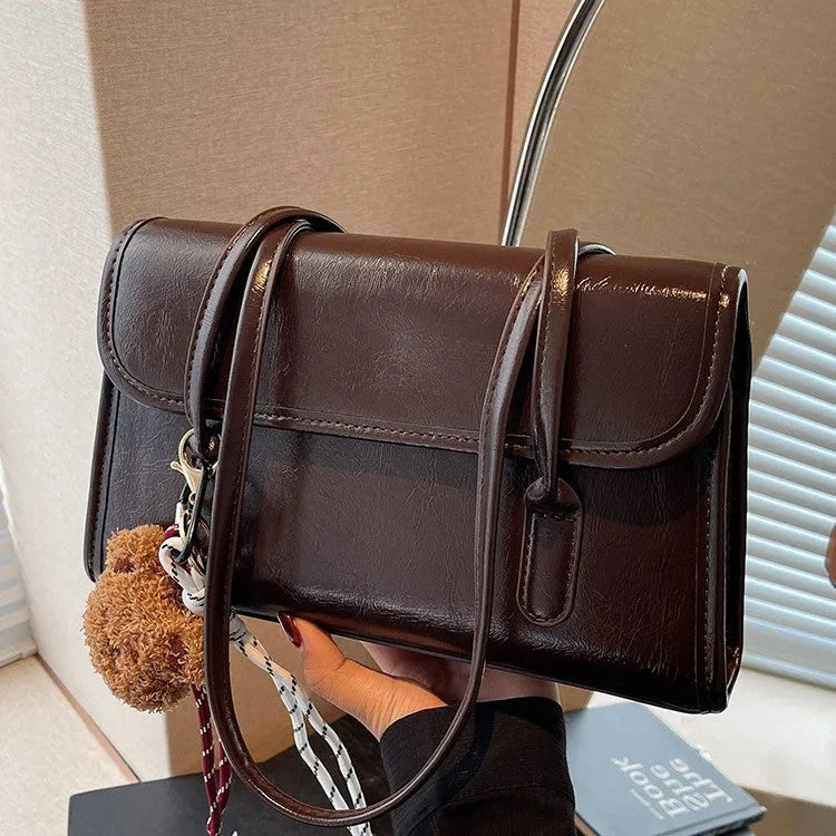 Women's brown PU leather shoulder bag with square shape, double straps, and decorative pendant attachment