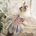 A small dog wearing a pink tartan plaid skirt in a Princess style.