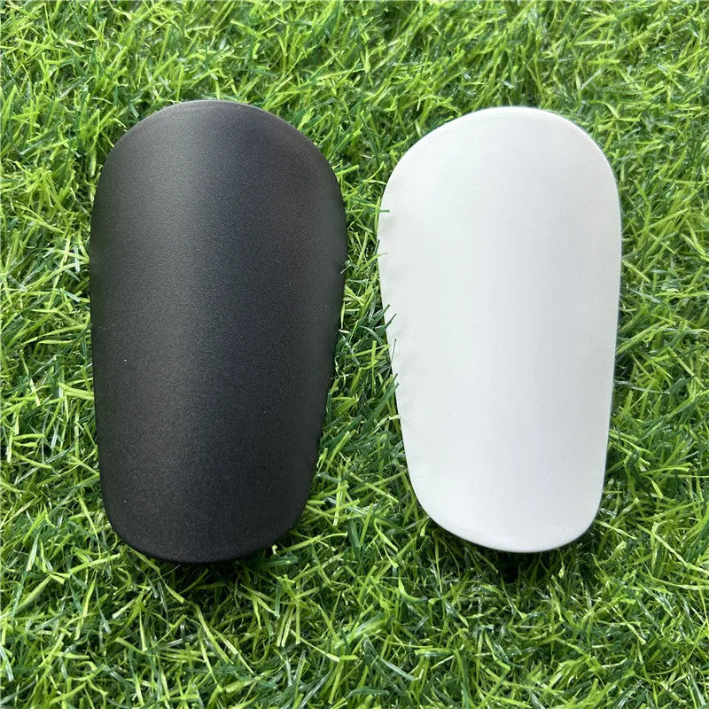 Pair of extra small black and white plastic football shin guards measuring 8x5cm for youth players