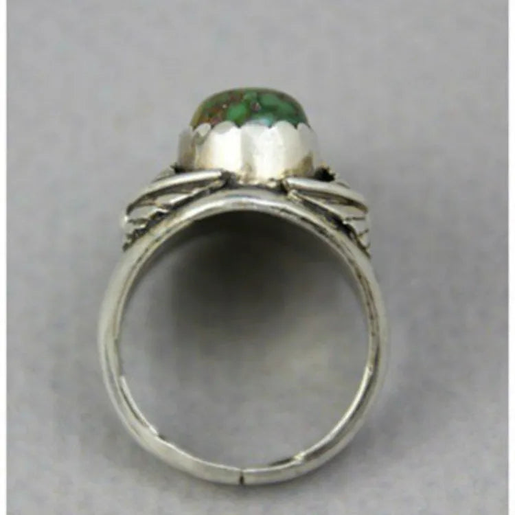 Close-up of a women's geometric turquoise ring with a retro inlaid design on a finger.