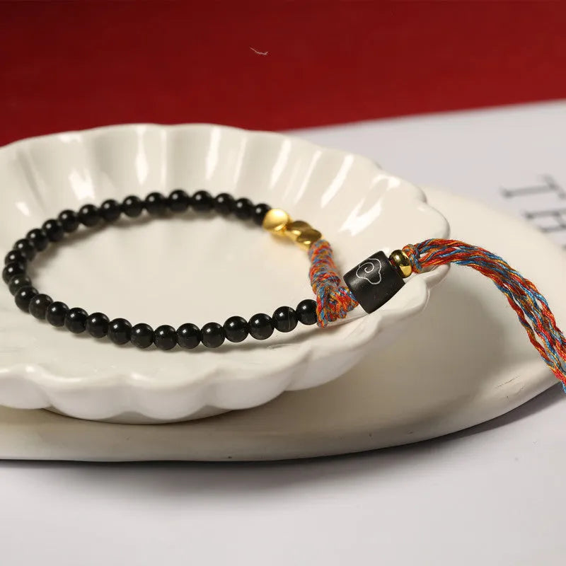 Hand-woven obsidian carrying strap bracelet showing textured weave and adjustable length