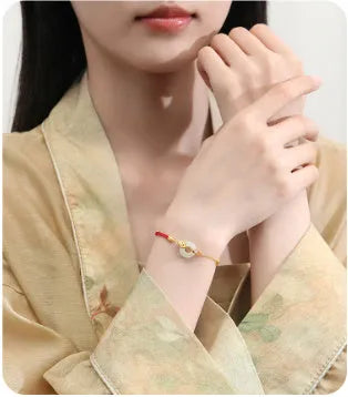 Women's red rope bracelet with silver and gold peace buckle charm featuring koi fish design