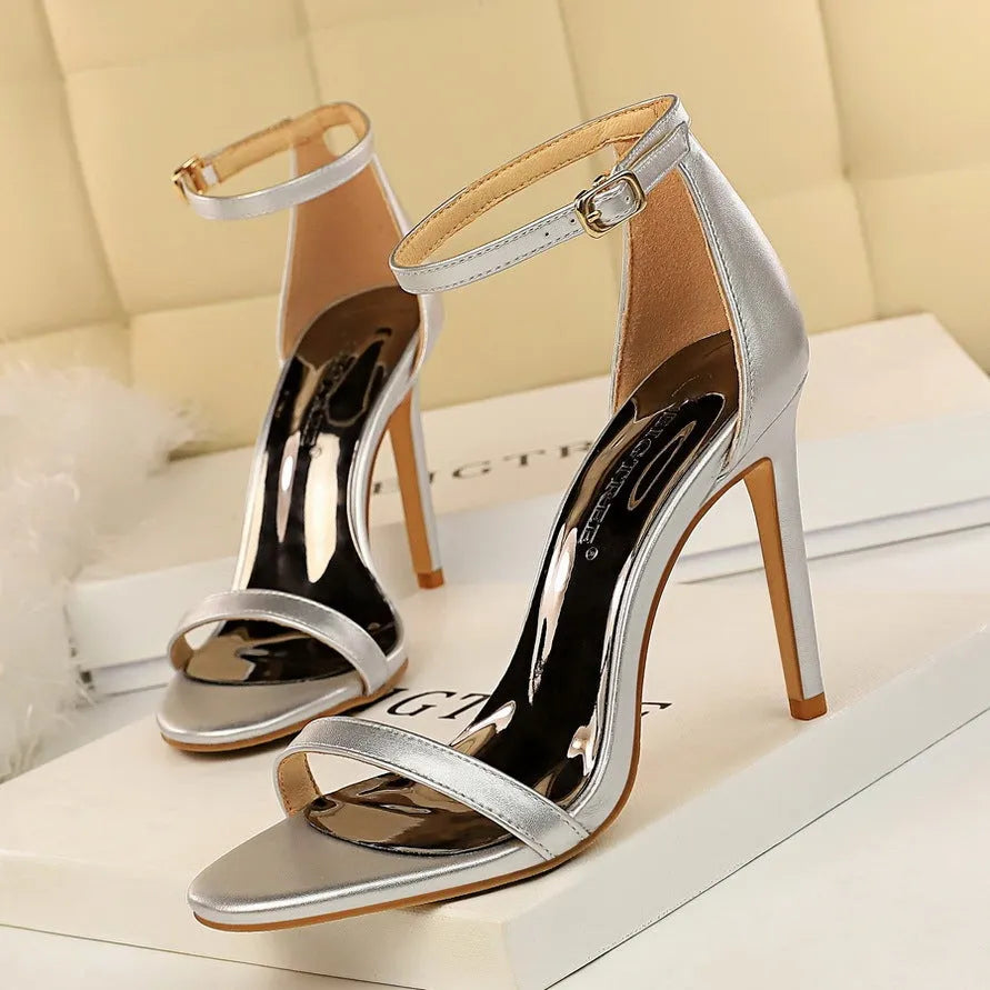 Women's open toe high heels with an ankle strap and buckle closure in a solid colour.