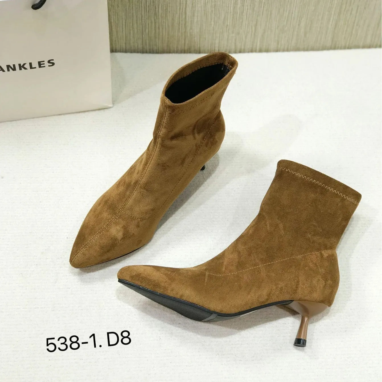 Black pointed toe women's ankle boots with a stiletto heel on a neutral background.