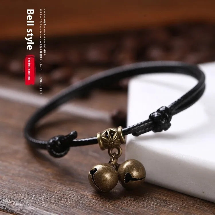 Nylon rope dog collar with brass bell on a black background, showing the adjustable rope and metal hardware.