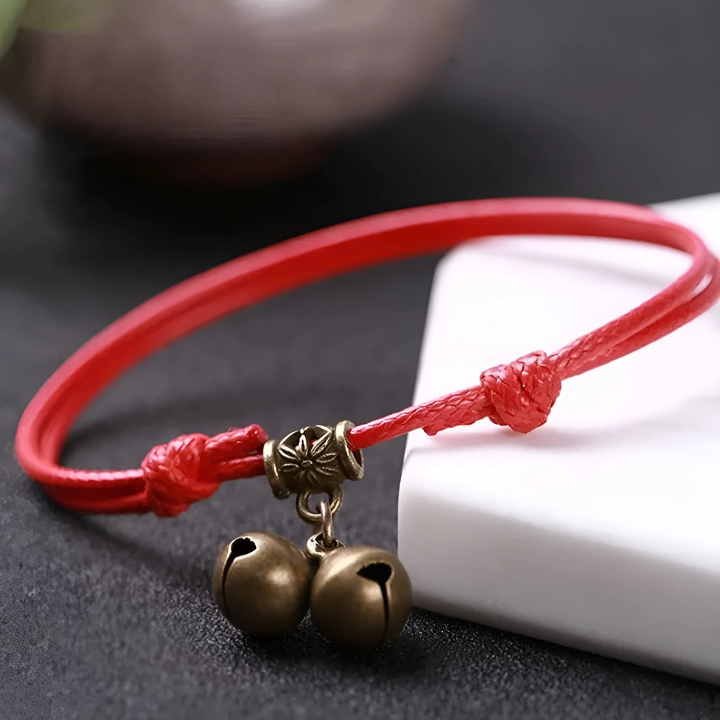 Nylon rope dog collar with brass bell on a black background, showing the adjustable rope and metal hardware.