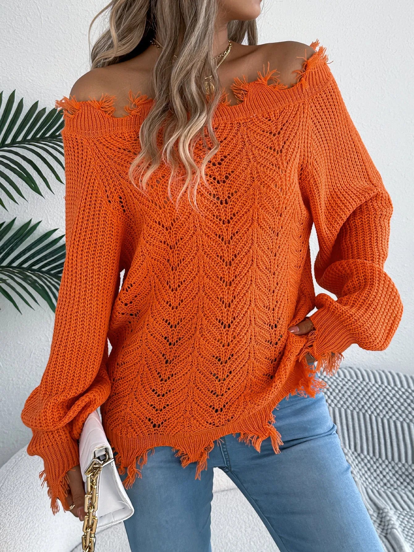 White women's hollow-out knit pullover sweater with long sleeves and an off-the-shoulder neckline.