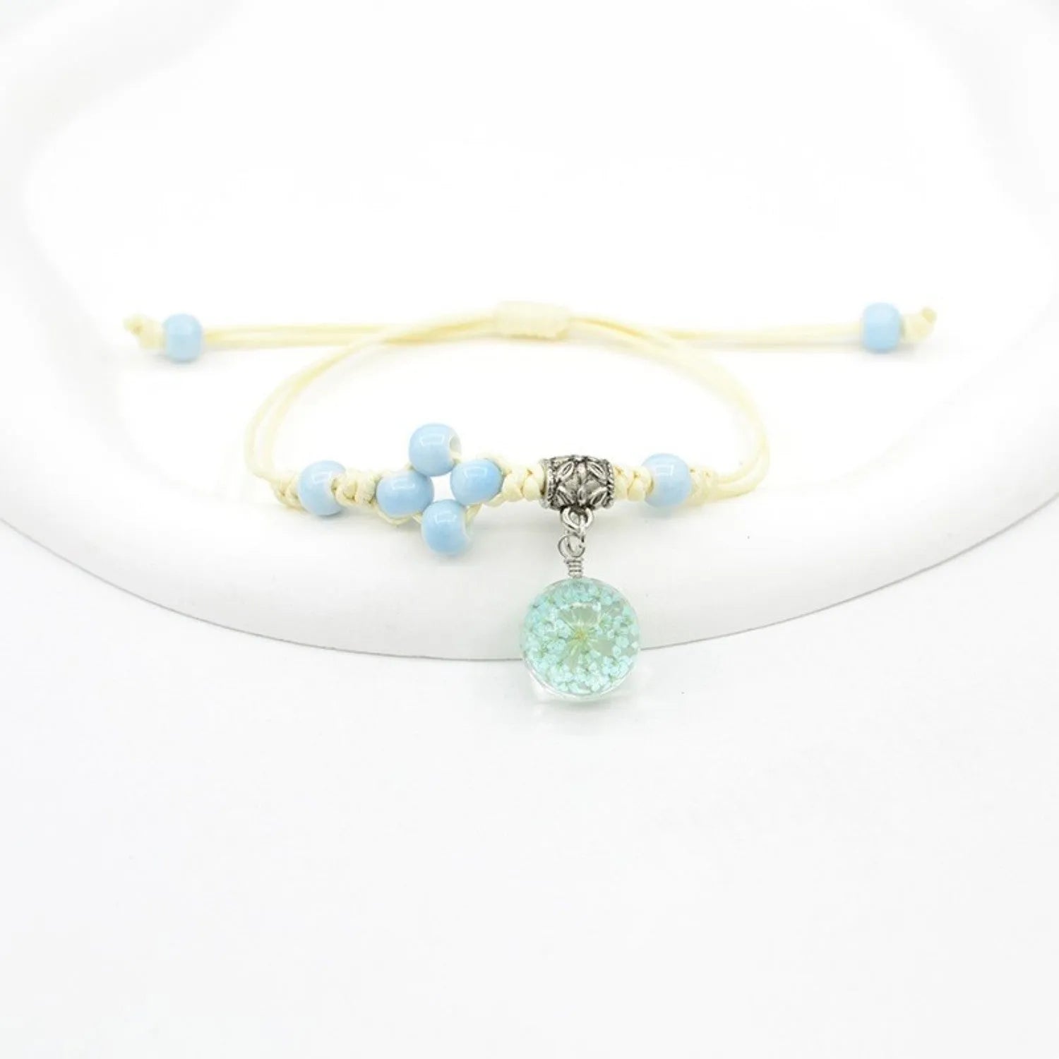 Close-up of a hand-woven glass bracelet with large 1.4 cm beads containing real dried flowers in multiple colour options.