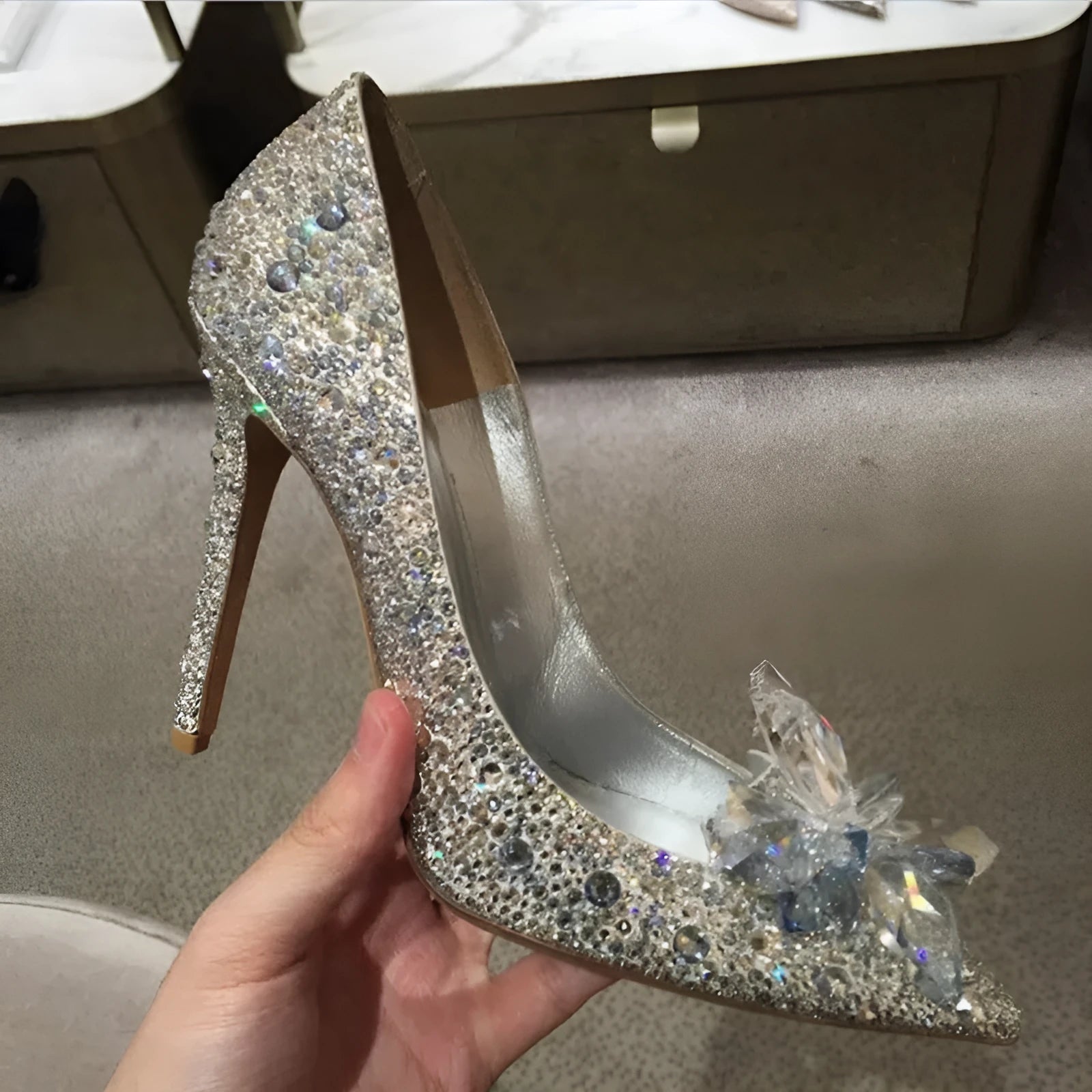 Gold women's pointed toe stiletto heels with rhinestone and bow decoration on a sequin cloth upper.