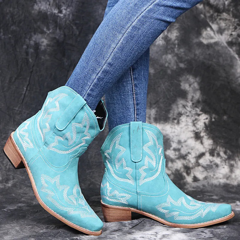 Women's blue embroidered cowboy boots with low wedge heel and pointed toe on a white background.