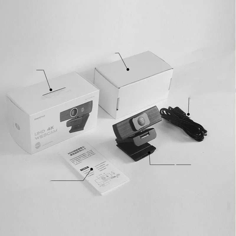 Black USB webcam with magnetic privacy cover on desk next to computer monitor