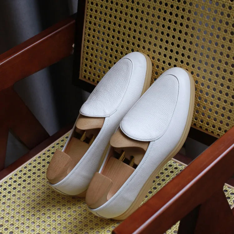 Men's brown genuine leather flat loafers with a low cut and TPR sole on a light background.