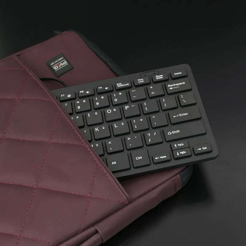 Compact black wired USB keyboard with noiseless keys on a desk.
