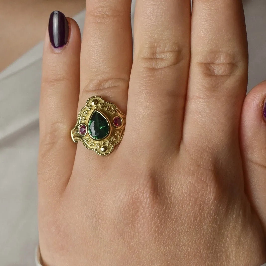 Geometric gold-coloured women's ring with an electroplated finish on a grey background.