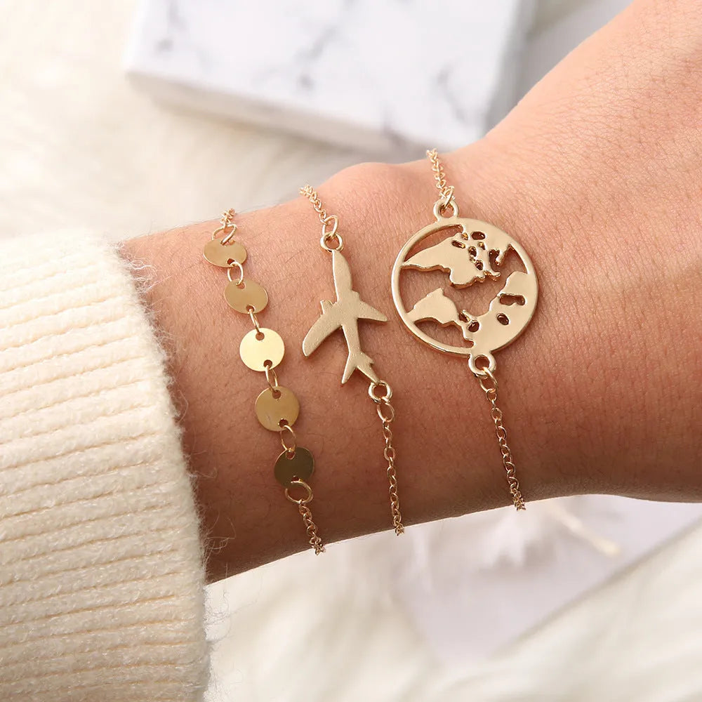 Three bohemian-style alloy bracelets with heart-shaped aircraft map charms on a white background.
