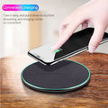 Black Qi wireless charging pad with built-in stand for iPhone 11 on a desk.