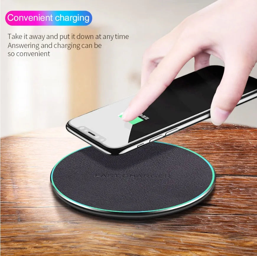 Black Qi wireless charging pad with built-in stand for iPhone 11 on a desk.