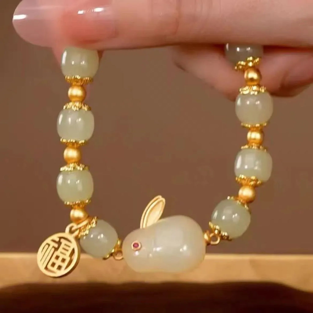 Green jade women's bracelet with a sculpted hare charm, engraved Fu character, and lily detailing