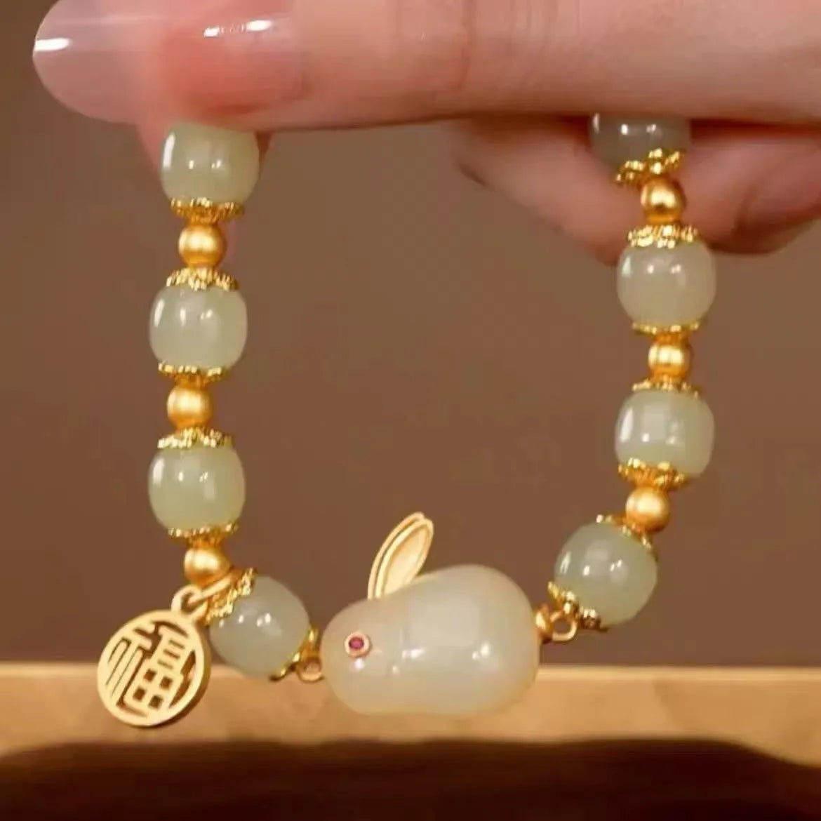 Green jade women's bracelet with a sculpted hare charm, engraved Fu character, and lily detailing